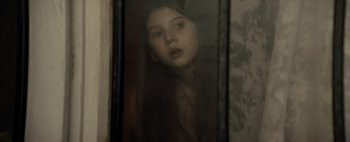 Movie still from “Don't Breathe 2” (2021), directed by Rodo Sayagues – A young girl looking out a window through a glass; Close Up shot, High angle