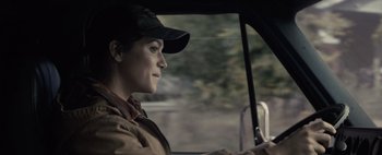 Movie still from “Don't Breathe 2” (2021), directed by Rodo Sayagues – A woman wearing a baseball cap driving in a car; Close Up shot, Over the shoulder angle