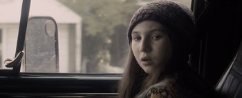 Movie still from “Don't Breathe 2” (2021), directed by Rodo Sayagues – A young girl wearing a hat looking out of a car window; Close Up shot, Over the shoulder angle