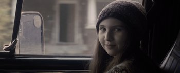 Movie still from “Don't Breathe 2” (2021), directed by Rodo Sayagues – A woman wearing a hat looking out of a window; Close Up shot, Over the shoulder angle