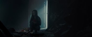 Movie still from “Don't Breathe 2” (2021), directed by Rodo Sayagues – A woman sitting in a dark room holding a flower; Wide shot, High angle