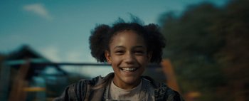 Movie still from “Don't Breathe 2” (2021), directed by Rodo Sayagues – A young girl smiling for the camera with her hair up; Close Up shot, Over the shoulder angle