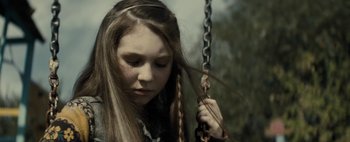 Movie still from “Don't Breathe 2” (2021), directed by Rodo Sayagues – A young girl with long brown hair is on a swing; Close Up shot, Over the shoulder angle