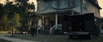 Movie still from “Don't Breathe 2” (2021), directed by Rodo Sayagues – A person standing outside of a house on the front lawn; Wide shot, Over the shoulder angle
