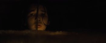 Movie still from “Don't Breathe 2” (2021), directed by Rodo Sayagues – A young girl looking out of a window at night; Close Up shot, Low angle