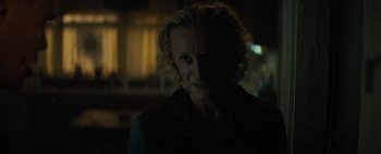 Movie still from “Don't Breathe 2” (2021), directed by Rodo Sayagues – A man with blonde curly hair and a smirking face; Close Up shot, Over the shoulder angle