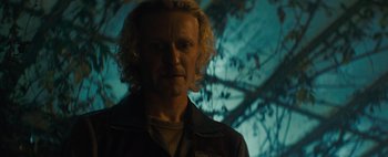 Movie still from “Don't Breathe 2” (2021), directed by Rodo Sayagues – A man with blonde curly hair standing in front of a tree; Close Up shot, Low angle