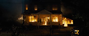 Movie still from “Don't Breathe 2” (2021), directed by Rodo Sayagues – A house with a porch lit up at night time; Extreme Wide shot, High angle