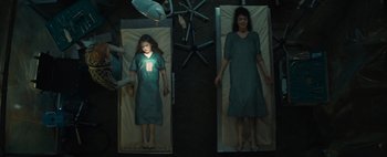 Movie still from “Don't Breathe 2” (2021), directed by Rodo Sayagues – A woman and a girl are laying in a hospital bed; Wide shot, Overhead angle