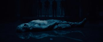Movie still from “Don't Breathe 2” (2021), directed by Rodo Sayagues – A man laying on the ground in a dark room; Wide shot, Overhead angle