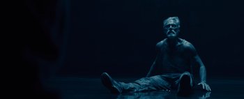 Movie still from “Don't Breathe 2” (2021), directed by Rodo Sayagues – A man sitting on the ground in a dark room; Wide shot, Low angle
