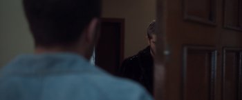 Movie still from “Don't Leave” (2022), directed by Ozan Açiktan – A man standing in front of a mirror in a room; Close Up shot, Over the shoulder angle