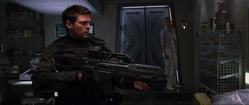 Movie still from “Doom” (2005), directed by Andrzej Bartkowiak – A man holding a gun while standing next to another man; Medium shot, Over the shoulder angle