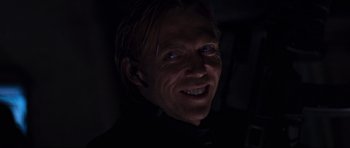 Movie still from “Doom” (2005), directed by Andrzej Bartkowiak – A person smiling with a dark background; Close Up shot, Low angle