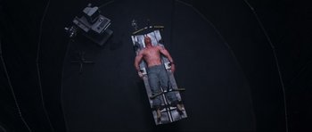 Movie still from “Doom” (2005), directed by Andrzej Bartkowiak – A man laying down on a bed in a room; Wide shot, Overhead angle