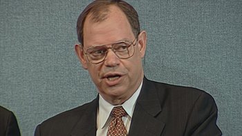 Movie still from “Downfall: The Case Against Boeing” (2022), directed by Rory Kennedy – An older man in a suit and tie; Close Up shot, High angle