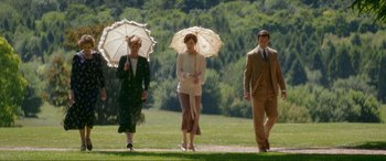 Movie still from “Downton Abbey: A New Era” (2022), directed by Simon Curtis – A group of people walking in a field with umbrellas; Wide shot, High angle