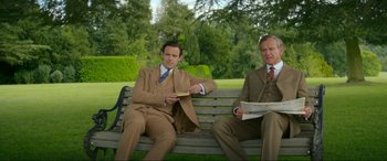 Movie still from “Downton Abbey: A New Era” (2022), directed by Simon Curtis – Two men sitting on a park bench in suits; Medium shot, High angle