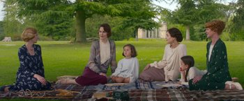 Movie still from “Downton Abbey: A New Era” (2022), directed by Simon Curtis – Three women sitting on a blanket in a park; Medium shot, Over the shoulder angle