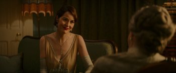 Movie still from “Downton Abbey: A New Era” (2022), directed by Simon Curtis – A woman sitting at a table in a room; Close Up shot, Over the shoulder angle