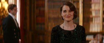 Movie still from “Downton Abbey: A New Era” (2022), directed by Simon Curtis – A woman standing in front of a book shelf; Close Up shot, Over the shoulder angle