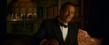 Movie still from “Downton Abbey: A New Era” (2022), directed by Simon Curtis – A man in a tuxedo standing in front of bookshelves; Close Up shot, Low angle