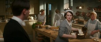 Movie still from “Downton Abbey: A New Era” (2022), directed by Simon Curtis – A group of people in a kitchen preparing food; Medium shot, Over the shoulder angle