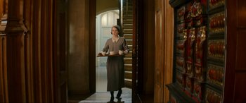 Movie still from “Downton Abbey: A New Era” (2022), directed by Simon Curtis – A woman holding a tray with two cups in front of a staircase; Wide shot, High angle