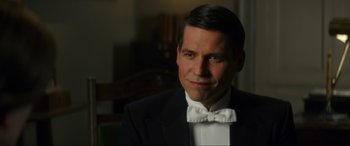 Movie still from “Downton Abbey: A New Era” (2022), directed by Simon Curtis – A person wearing a suit and bow tie; Close Up shot, Over the shoulder angle