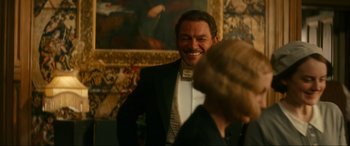 Movie still from “Downton Abbey: A New Era” (2022), directed by Simon Curtis – A man in a tuxedo smiling at a woman in a black suit; Medium shot, Over the shoulder angle