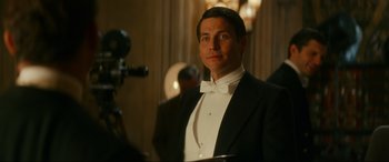 Movie still from “Downton Abbey: A New Era” (2022), directed by Simon Curtis – A man in a tuxedo standing in front of a camera; Close Up shot, Over the shoulder angle
