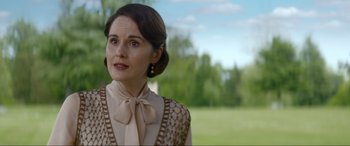 Movie still from “Downton Abbey: A New Era” (2022), directed by Simon Curtis – A woman in a brown and white dress looking to her left; Close Up shot, Over the shoulder angle