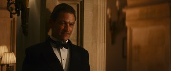 Movie still from “Downton Abbey: A New Era” (2022), directed by Simon Curtis – A man in a tuxedo standing in front of a wall; Close Up shot, Low angle
