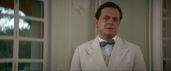 Movie still from “Downton Abbey: A New Era” (2022), directed by Simon Curtis – A man wearing a suit and bow tie; Close Up shot, Low angle