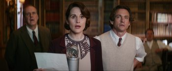 Movie still from “Downton Abbey: A New Era” (2022), directed by Simon Curtis – A woman standing next to a man in a library; Medium shot, Low angle