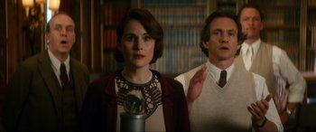 Movie still from “Downton Abbey: A New Era” (2022), directed by Simon Curtis – A man and a woman standing next to each other in a library; Medium shot, Low angle