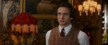Movie still from “Downton Abbey: A New Era” (2022), directed by Simon Curtis – A person wearing a vest and a tie; Medium shot, Over the shoulder angle