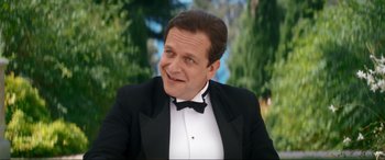 Movie still from “Downton Abbey: A New Era” (2022), directed by Simon Curtis – A man in a tuxedo is smiling for the camera; Close Up shot, Over the shoulder angle