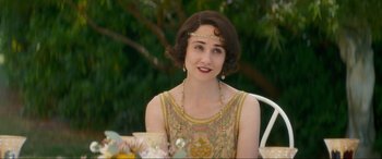 Movie still from “Downton Abbey: A New Era” (2022), directed by Simon Curtis – A woman in a dress sitting in front of a tree; Close Up shot, High angle