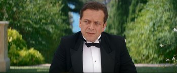 Movie still from “Downton Abbey: A New Era” (2022), directed by Simon Curtis – A person wearing a suit and bow tie; Close Up shot, Over the shoulder angle