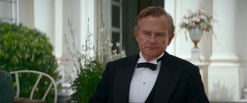 Movie still from “Downton Abbey: A New Era” (2022), directed by Simon Curtis – An older man in a black suit and a bow tie; Close Up shot, Over the shoulder angle