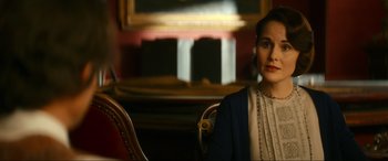 Movie still from “Downton Abbey: A New Era” (2022), directed by Simon Curtis – A woman sitting in a chair in front of a painting; Close Up shot, Over the shoulder angle