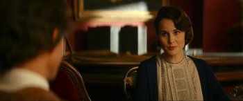 Movie still from “Downton Abbey: A New Era” (2022), directed by Simon Curtis – A woman sitting in a chair in front of a painting; Close Up shot, Over the shoulder angle