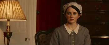 Movie still from “Downton Abbey: A New Era” (2022), directed by Simon Curtis – A woman wearing a hat sitting in a chair; Close Up shot, Over the shoulder angle