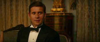 Movie still from “Downton Abbey: A New Era” (2022), directed by Simon Curtis – A man in a tuxedo is posing for a picture; Close Up shot, Over the shoulder angle
