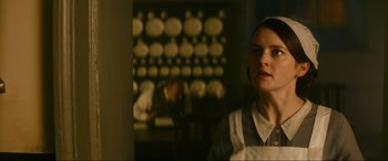 Movie still from “Downton Abbey: A New Era” (2022), directed by Simon Curtis – A woman standing in front of a wall with bowls on the wall; Close Up shot, Low angle