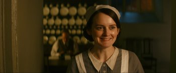 Movie still from “Downton Abbey: A New Era” (2022), directed by Simon Curtis – A woman wearing a white hat and a dress smiling for the camera; Close Up shot, Over the shoulder angle