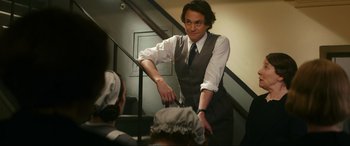 Movie still from “Downton Abbey: A New Era” (2022), directed by Simon Curtis – A man standing on a staircase holding a sword; Medium shot, Over the shoulder angle