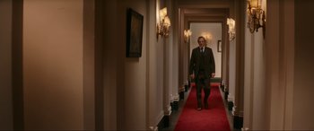 Movie still from “Downton Abbey: A New Era” (2022), directed by Simon Curtis – A man walking down a hallway in a suit and tie; Wide shot, Low angle