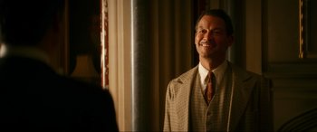 Movie still from “Downton Abbey: A New Era” (2022), directed by Simon Curtis – A man wearing a suit and tie smiling; Close Up shot, Over the shoulder angle